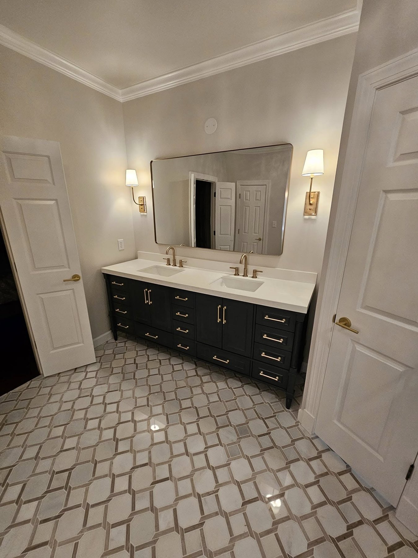 Bathroom renovation with dark double vanity, mirrors, and patterned tile floor