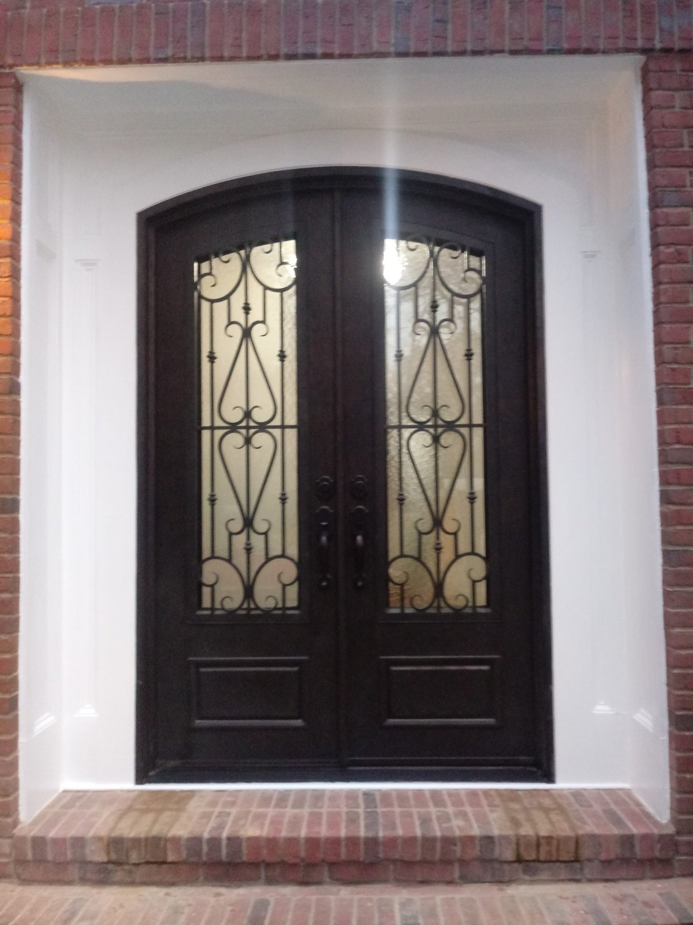 Decorative black double entry doors installed in a brick home