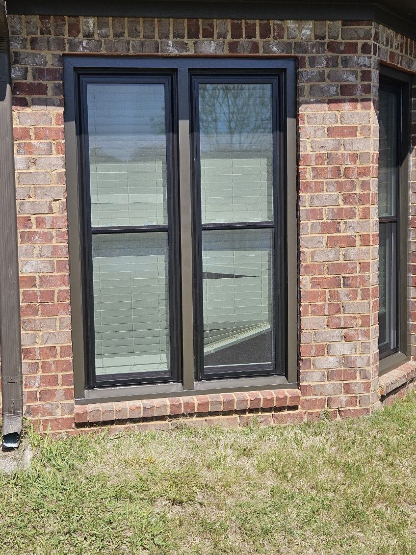 Black framed replacement window installed in a brick exterior wall