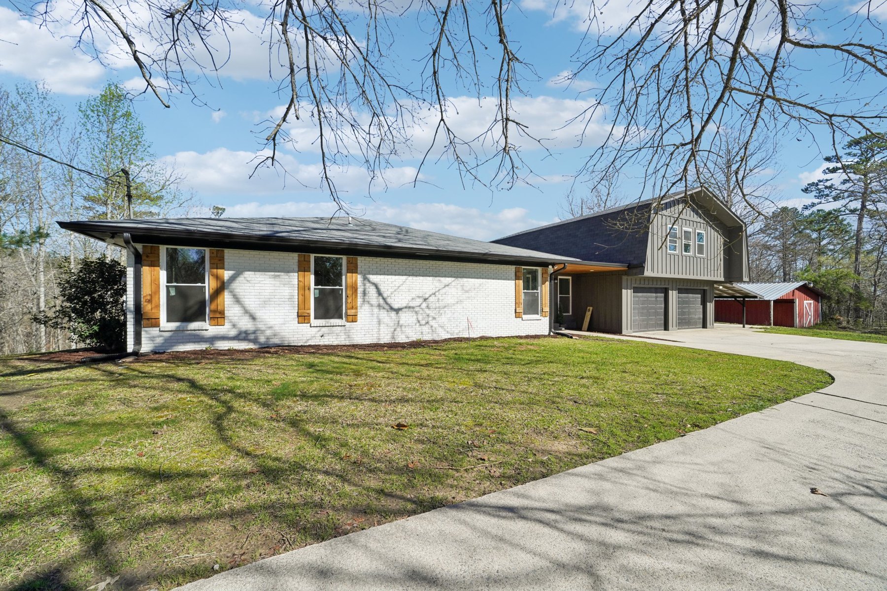 White single-story home after exterior renovation with dark roof and wood shutters