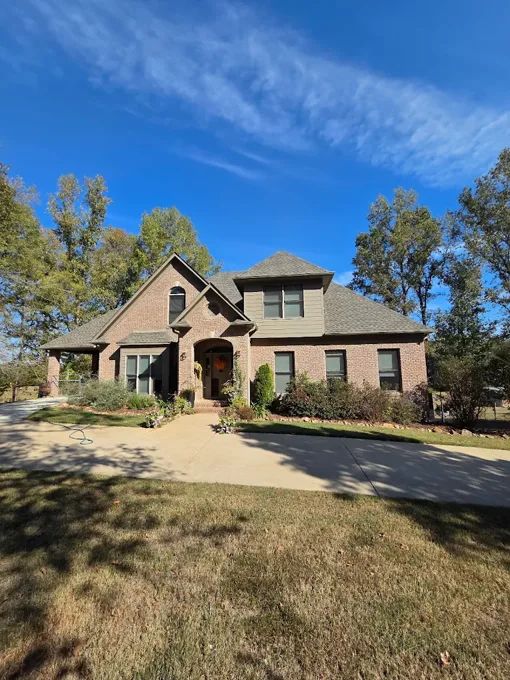 Brick home with shingle roofing, front gables, and a curved driveway