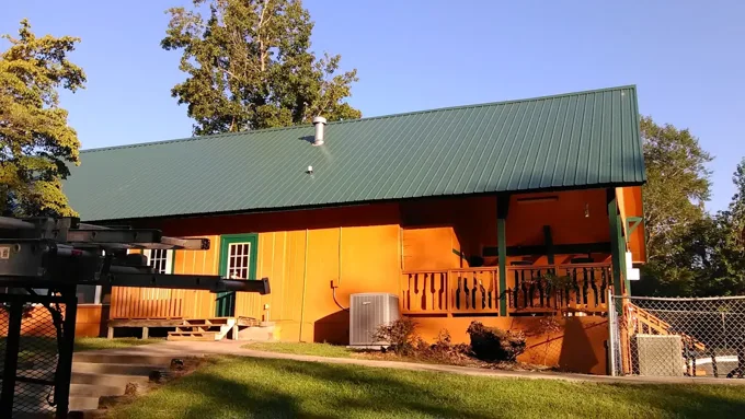 Green metal roofing above orange siding and a wood porch