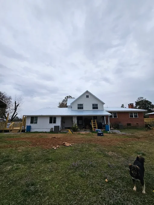 Rear of a farmhouse with a metal roof and exterior work in progress