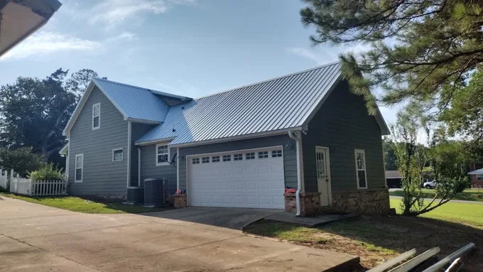 Metal roofing above a gray home and attached garage