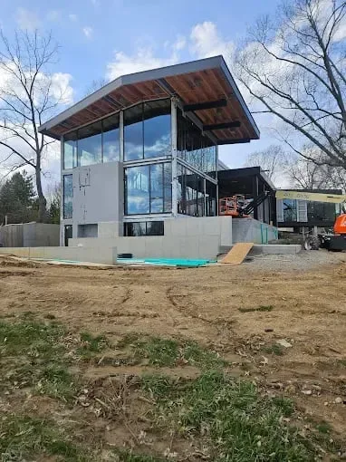 Modern home under construction with tall glass windows and a broad overhang