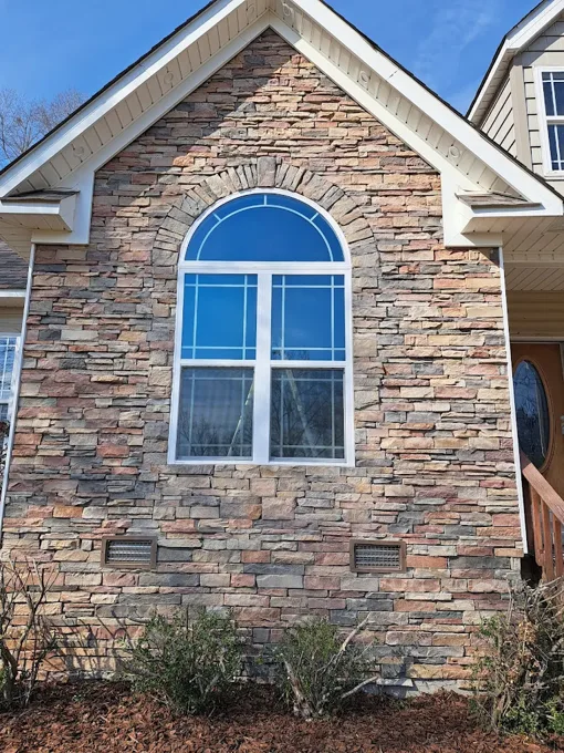 Stone exterior around an arched window with white trim